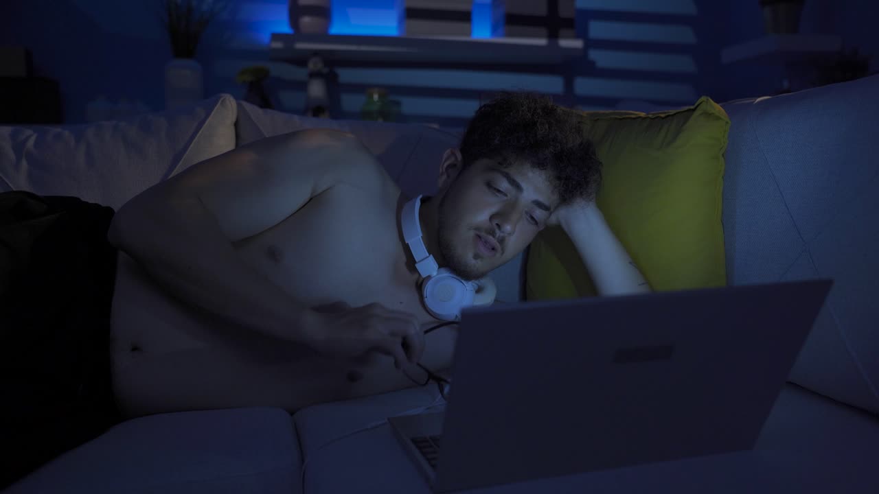 un joven que usa una computadora portátil piensa y escribe en el teclado.