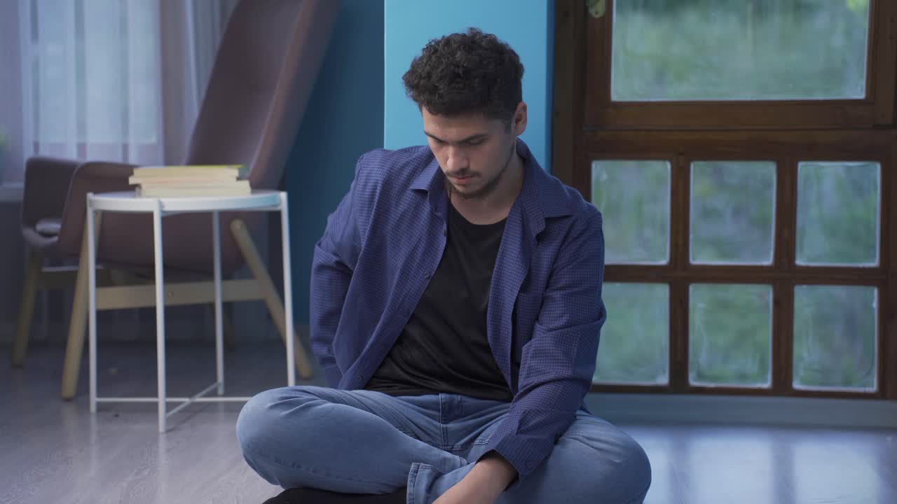 The man sitting by the wall looks at his empty wallet. Broke.