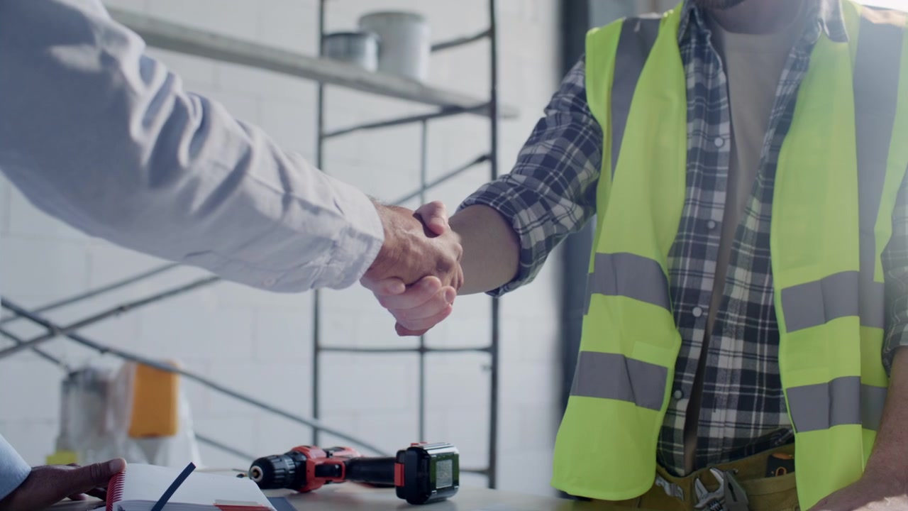 Close-up de Empreiteiro e Arquiteto Apertando as Mãos no Canteiro de Obras