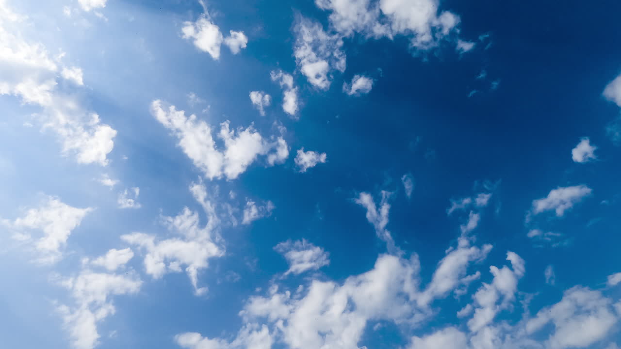 Light white clouds spreading along the blue skies. Beautiful cotton clouds looking heavenly in the sun rays. Timelapse.