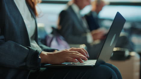 businesswoman typing on laptop in airport waiting area