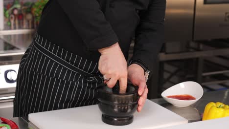 chef usando mortero y pestillo para preparar especias