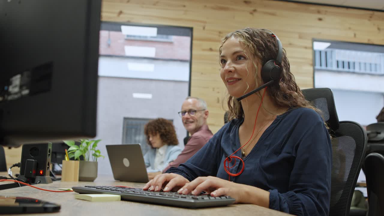 Woman working at computer with headset in office