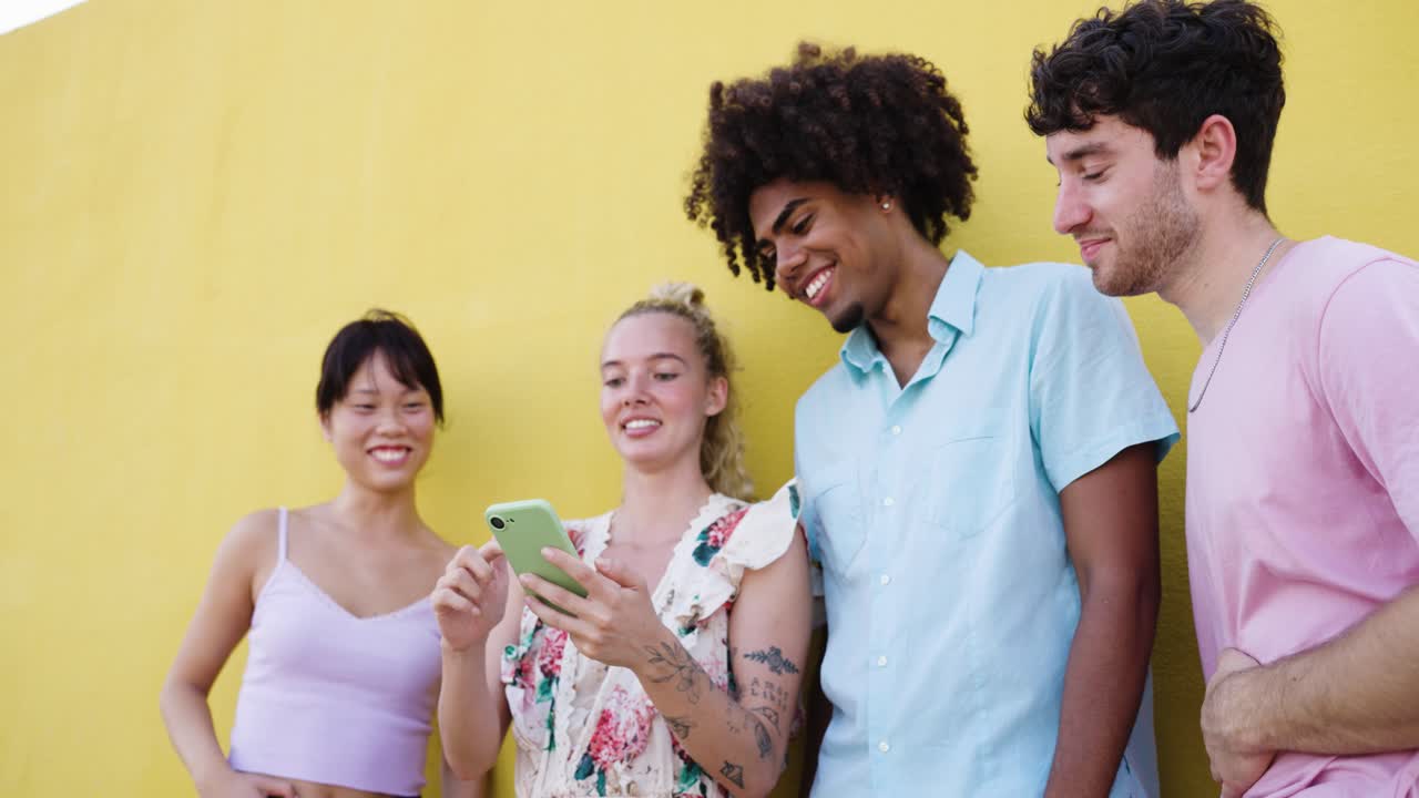 Amici che si godono contenuti visivi su un telefono cellulare su sfondo giallo