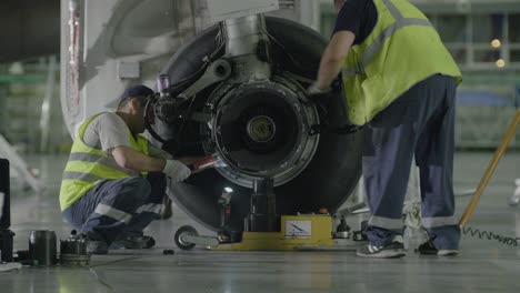 mecánicos de aviones que trabajan en el pozo de la rueda del avión