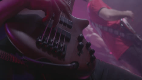 beautiful slow motion shot of a bassist harshly playing his bass with his fingers during a live performance or concert