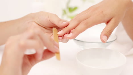 beautician filing female clients nails at spa beauty salon