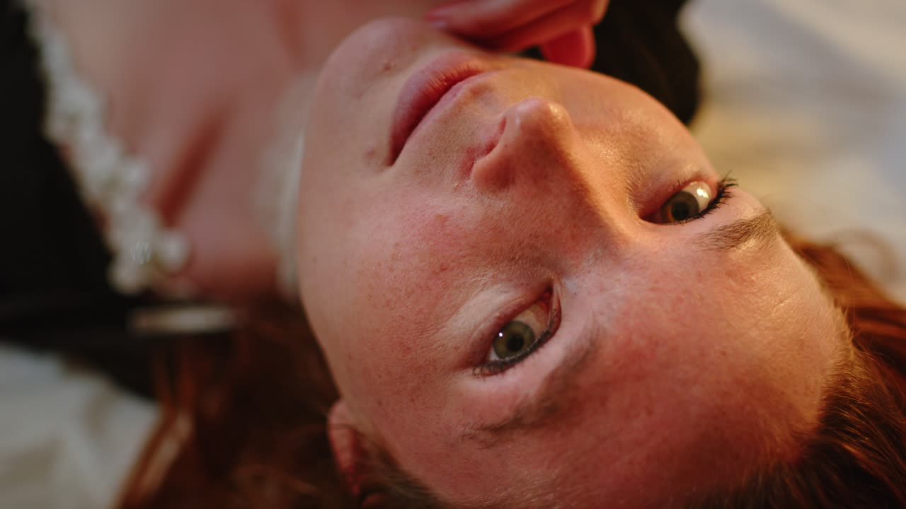 Bela mulher ruiva deitada na cama olhando para a câmera.