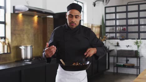 cocinero de raza mixta preparando un plato y sonriendo en una cocina