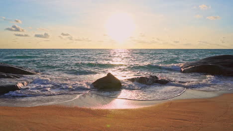 Hermosa-Puesta-De-Sol-Frente-Al-Mar---Olas-Rodando-Sobre-Piedras-A-La-Playa-De-Arena-En-Una-Isla-Salvaje-En-Tailandia