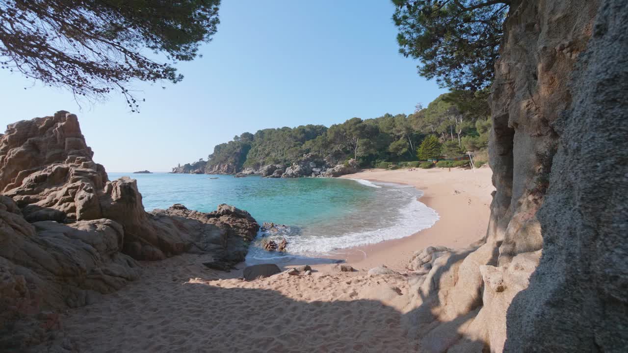 Bellissima spiaggia di sabbia rosa con onde di acqua color turchese che si infrangono sulla riva, Spagna