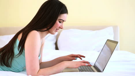 mujer alegre escribiendo en su portátil