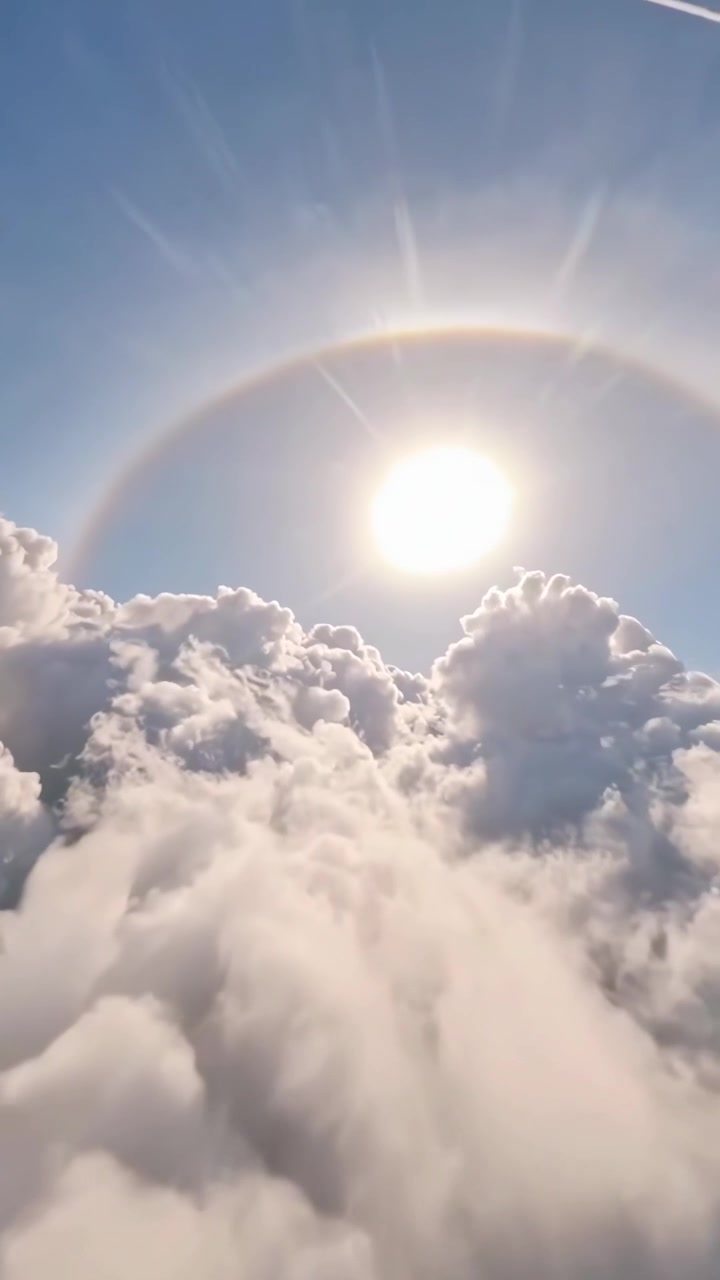 Vista aerea di alone solare sopra le nuvole con scia di aereo