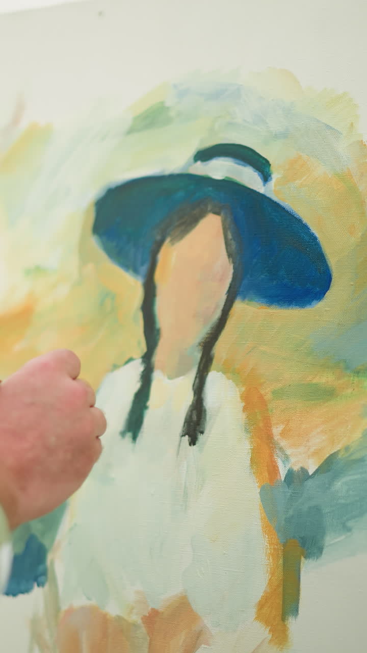 체크색 셔츠와 모자를 입은 화가가 캔버스에 생동감 넘치는 초상화를 조심스럽게 만들고 있습니다. 클로즈업 은 조심스러운 브러쉬 스트로크와 예술 작품에 대한 예술가의 초점을 강조합니다.