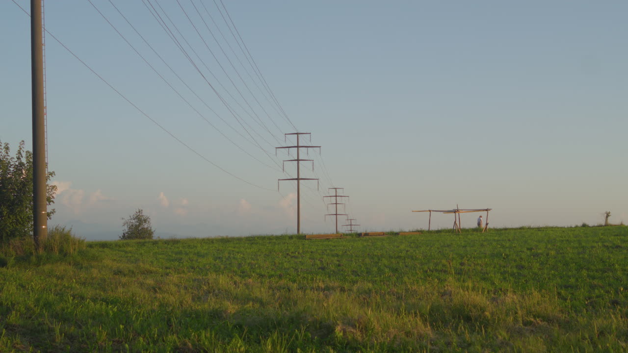 Woman walking on a footpath with power poles on a summer day, Switzerland