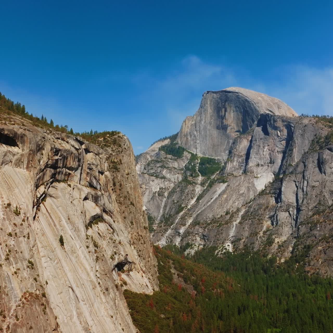 Magnificent grey mountains with some pine trees growing on tops. Splendid cliffs at backdrop of blue sky