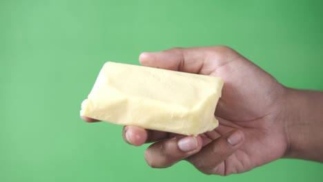 hand hold butter against green background