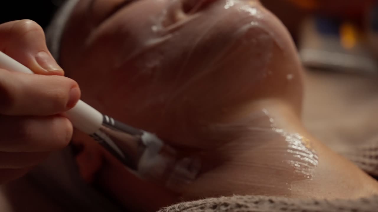 Estetista che applica una maschera viso sul volto e sul collo di una donna