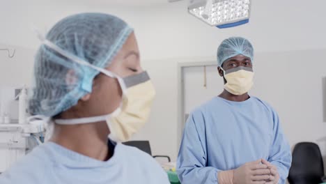 Portrait-of-happy-diverse-surgeons-with-face-masks-in-operating-room-in-slow-motion,-unaltered