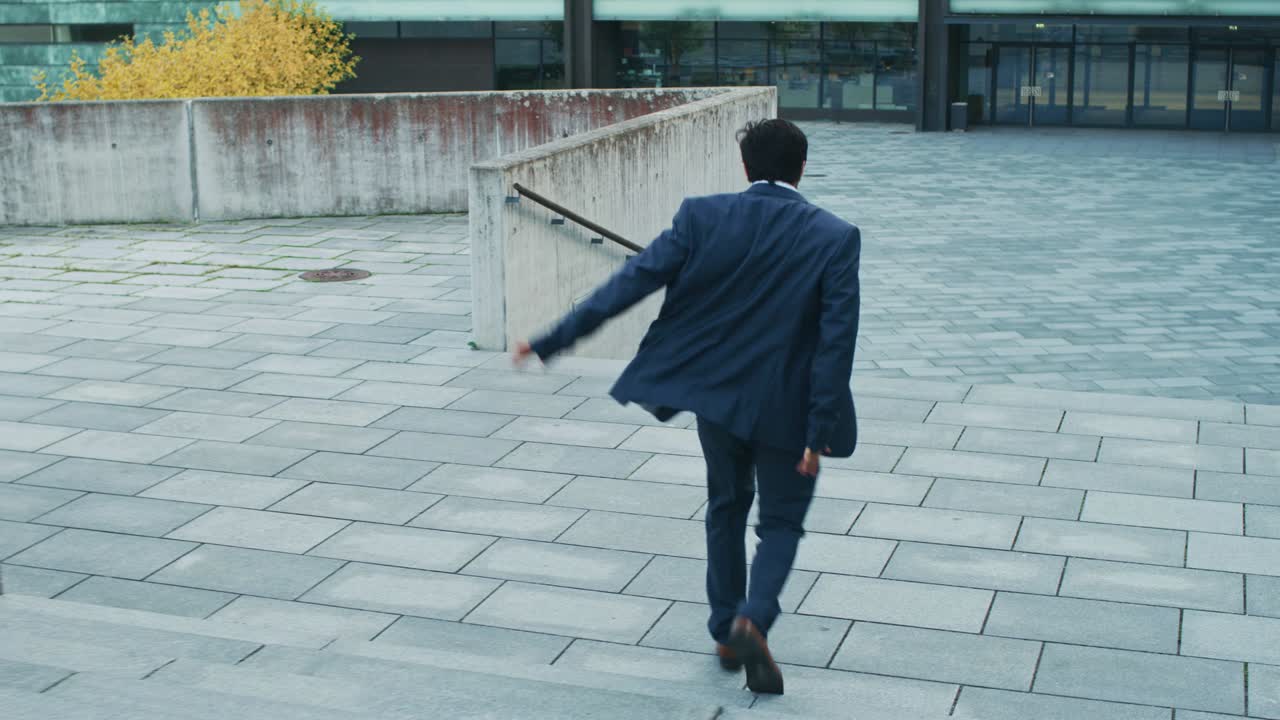 Cheerful and Happy Businessman in a Suit Actively Dancing While Walking Down the Stairs. Scene Shot in an Urban Concrete Park Next to a Business Center. Sunny Day.