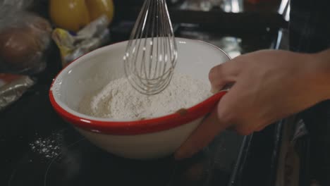 hand mixing dry ingredients in a bowl using wire whip - close up