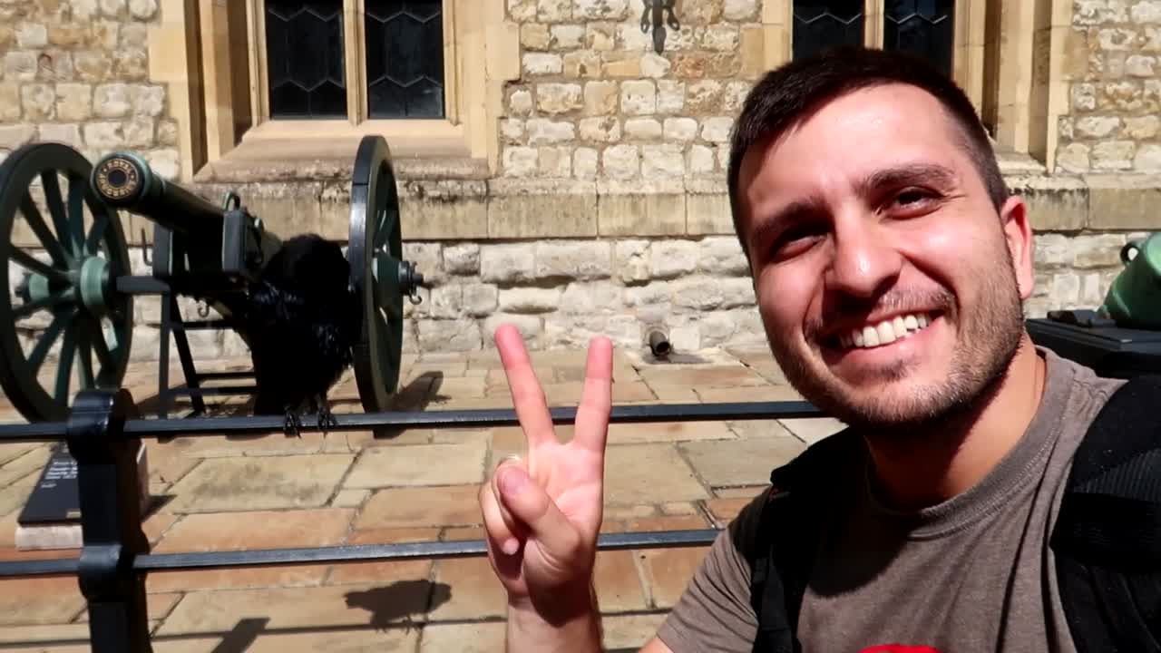 feliz joven turista caucásico sonriendo en la torre de londres con un cuervo