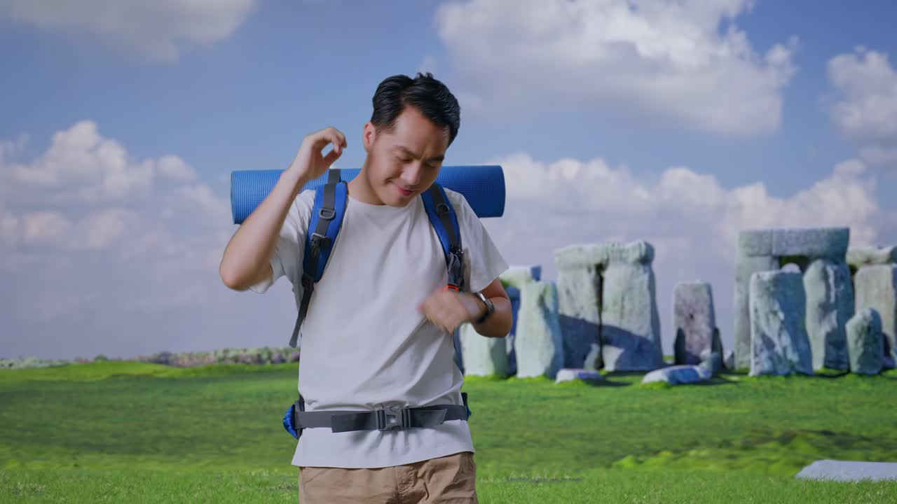 Asian Male Hiker With Mountaineering Backpack Enjoy Dancing While Traveling In Stonehenge