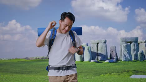 asian male hiker with mountaineering backpack enjoy dancing while traveling in stonehenge