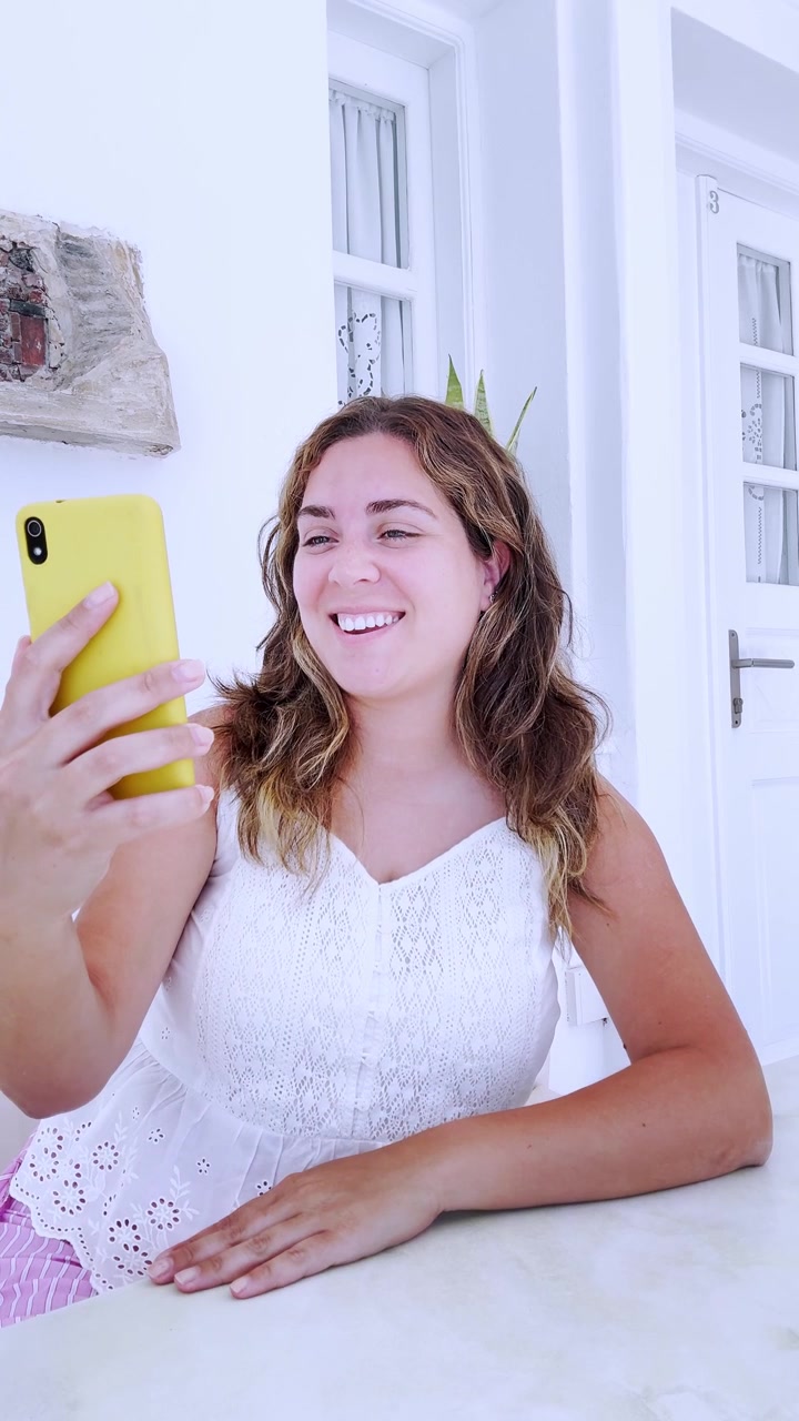 Viaggiatrice che usa il telefono per una videochiamata a Santorini