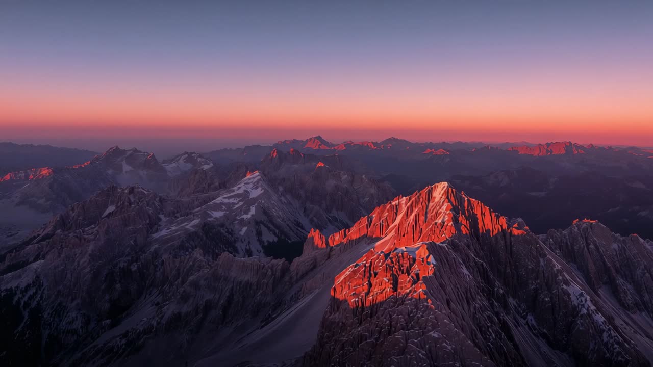 Sunrise rays catching peaks, highlighting snow patches across rocky ridge at dawn, with pastel sky