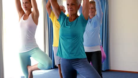 Trainer-assisting-senior-citizens-in-practicing-yoga