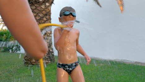 child and mom having fun time with water in the yard