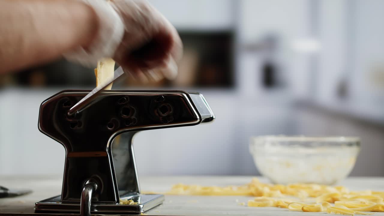 Close-up of Hands Making Fresh Pasta Noodles with a Machine