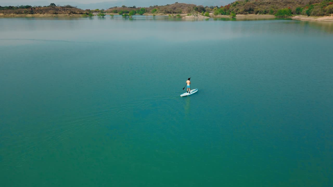 Vista aerea di una persona che fa paddleboard su un lago calmo