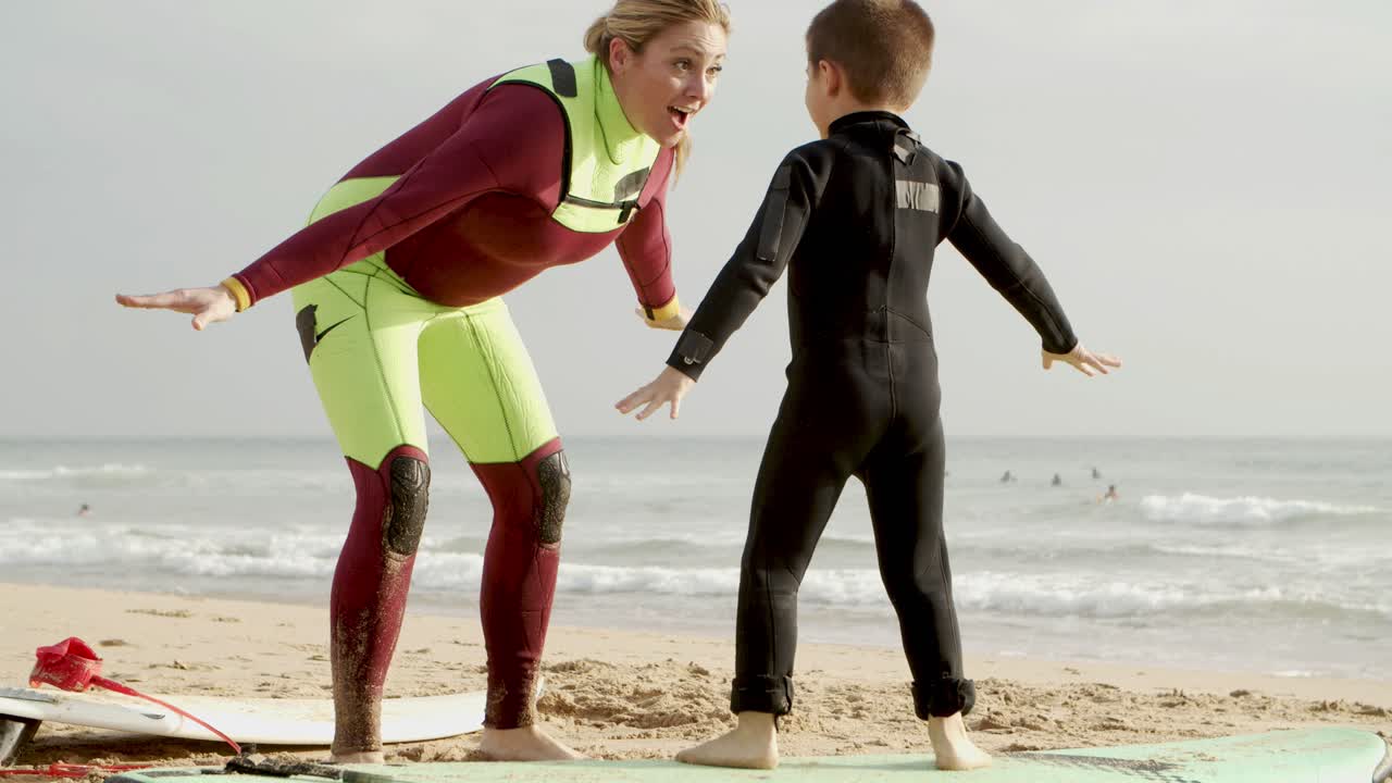 Mother and son with surfboards on beach