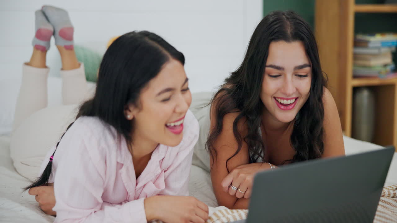 Two women watching a laptop in bed