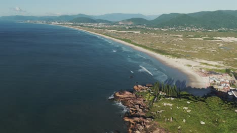 a dynamic upward motion reveals the expansive stretch of joaquina beach, showcasing its vast beauty and inviting shores