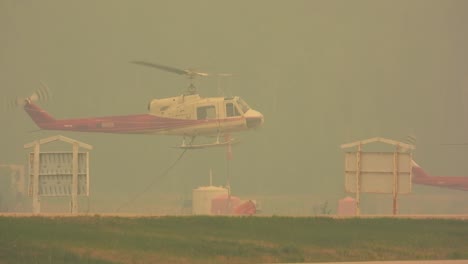 water-dropping helicopter takes off from a smoke-filled airport sky