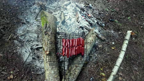 Top-view-of-sausages-roasting-on-a-campfire-with-a-grill