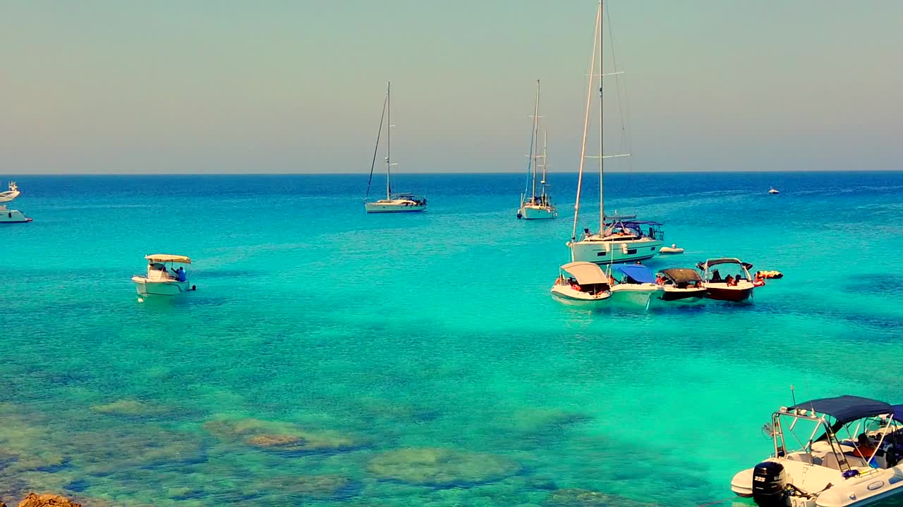 cacerola lenta que revela muchos barcos con su ancla bajada en una cala tranquila en el cabo greco, chipre