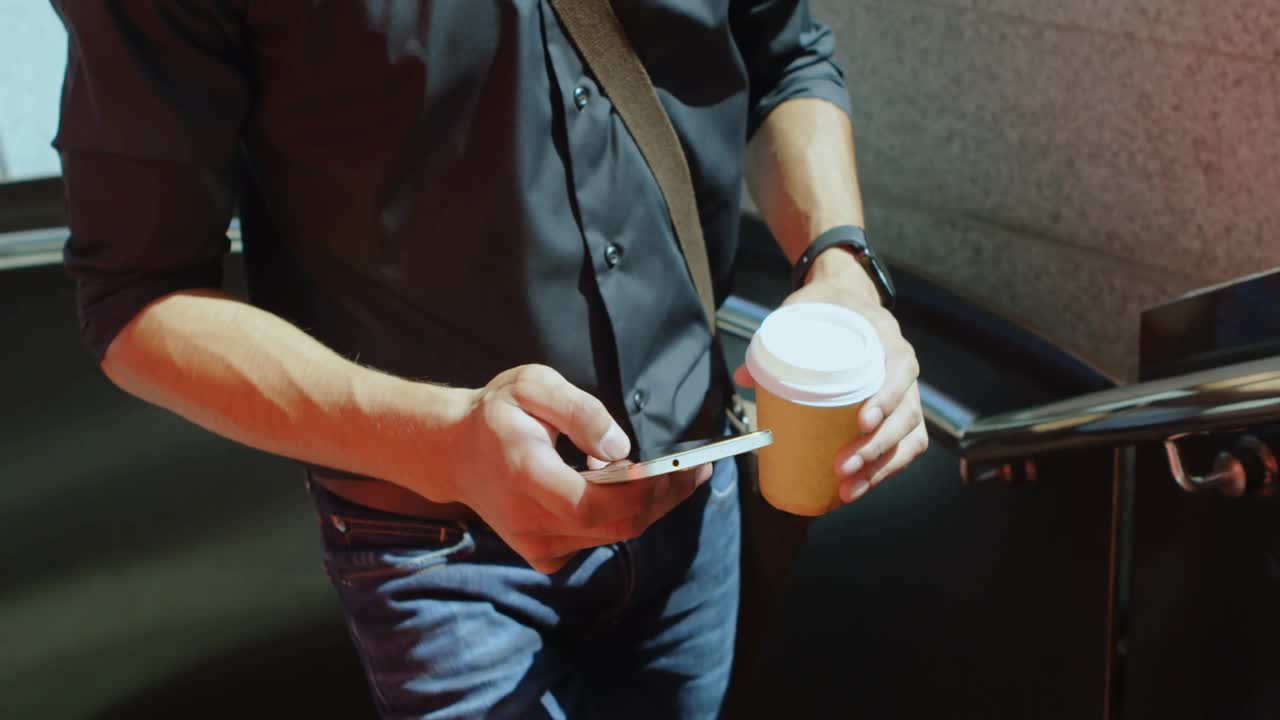 Man tapping phone, checking messages on stairs with coffee, bubbles rising around phone to 60 tech