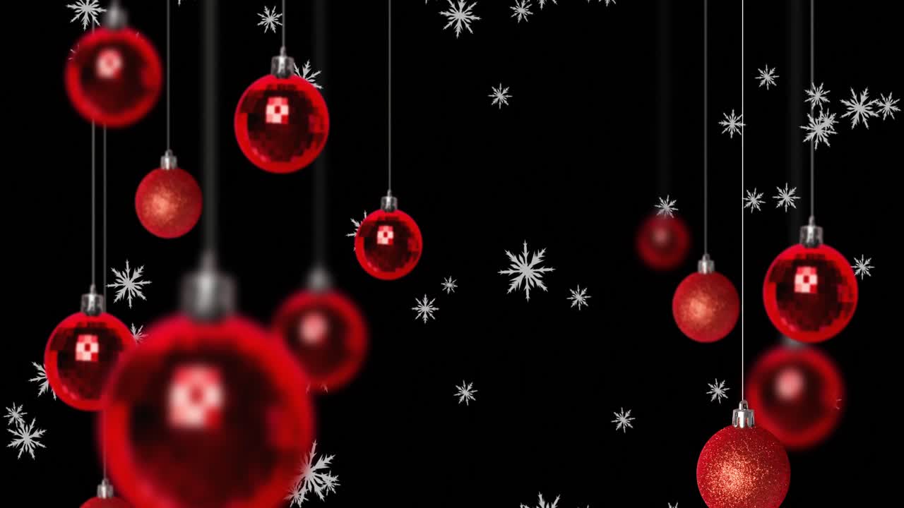 animación digital de copos de nieve cayendo sobre las bolas rojas de navidad colgando contra un fondo negro