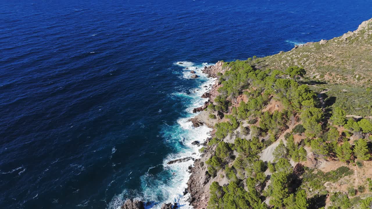 Onde blu intenso del Mar Mediterraneo che si infrangono sulle scogliere rocciose a Maiorca, Spagna
