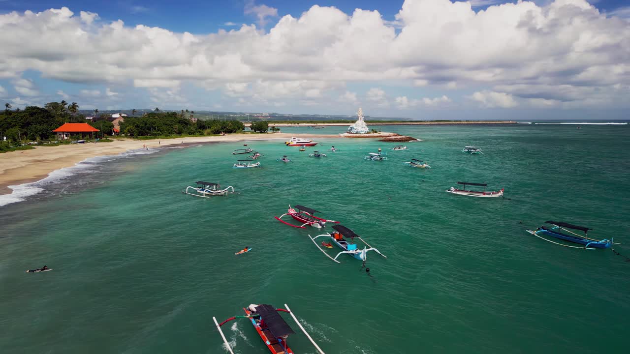 traditional fishing boats rest on the shore as surfers prepare for their trip into the waves of bali captured in a calm morning drone view showing both old traditions and modern adventures
