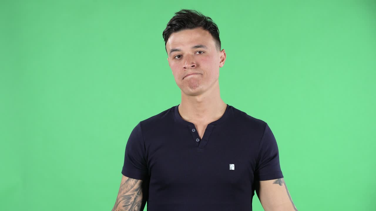 똑바로 보이는 잘생긴 젊은 남자의 초상화 어깨를 끄덕여 보여주는 나는 모른다. 녹색 화면