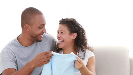 cute couple on the sofa holding a baby clothes