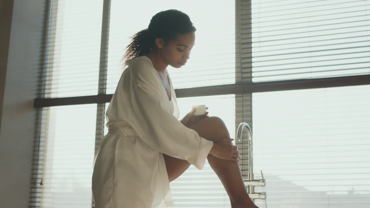 Woman Applying Lotion in a Luxurious Bathroom