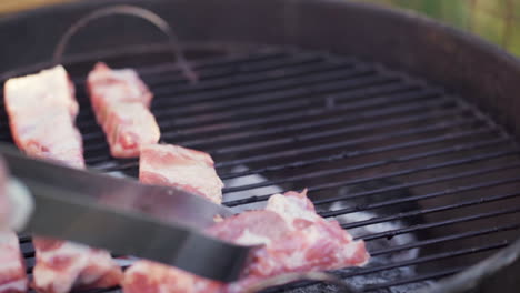 slow motion of tongs laying meat on smokey bbq grill