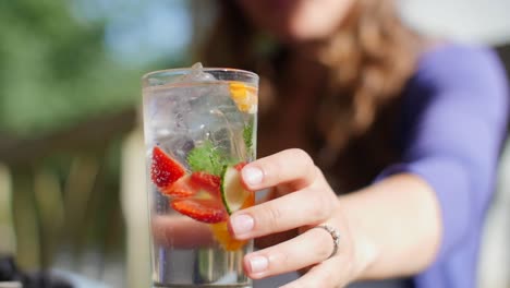 lady picking up glass of summer cocktail