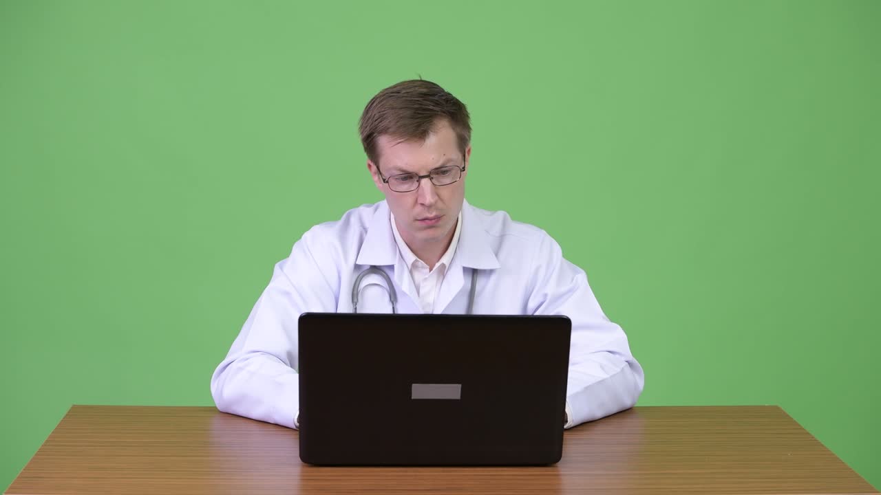 Portrait Of Young Man Doctor Sitting And Using Laptop Computer